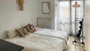 Un dormitorio con dos camas, un armario, un espejo y una percha.