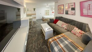 Una sala de estar moderna con sofá, mesa de centro, mesa de comedor y zona de cocina.