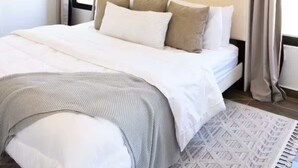 Una cama bien hecha con cabecera, un tapete estampado y un adorno de pared.