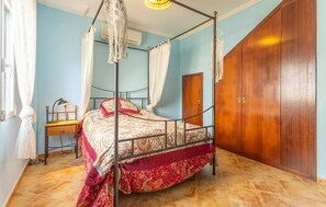 Un lit à baldaquin, une armoire en bois et un bureau avec une lampe.
