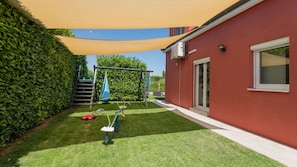 Un jardin avec une balançoire, un toboggan et une structure d’escalade.