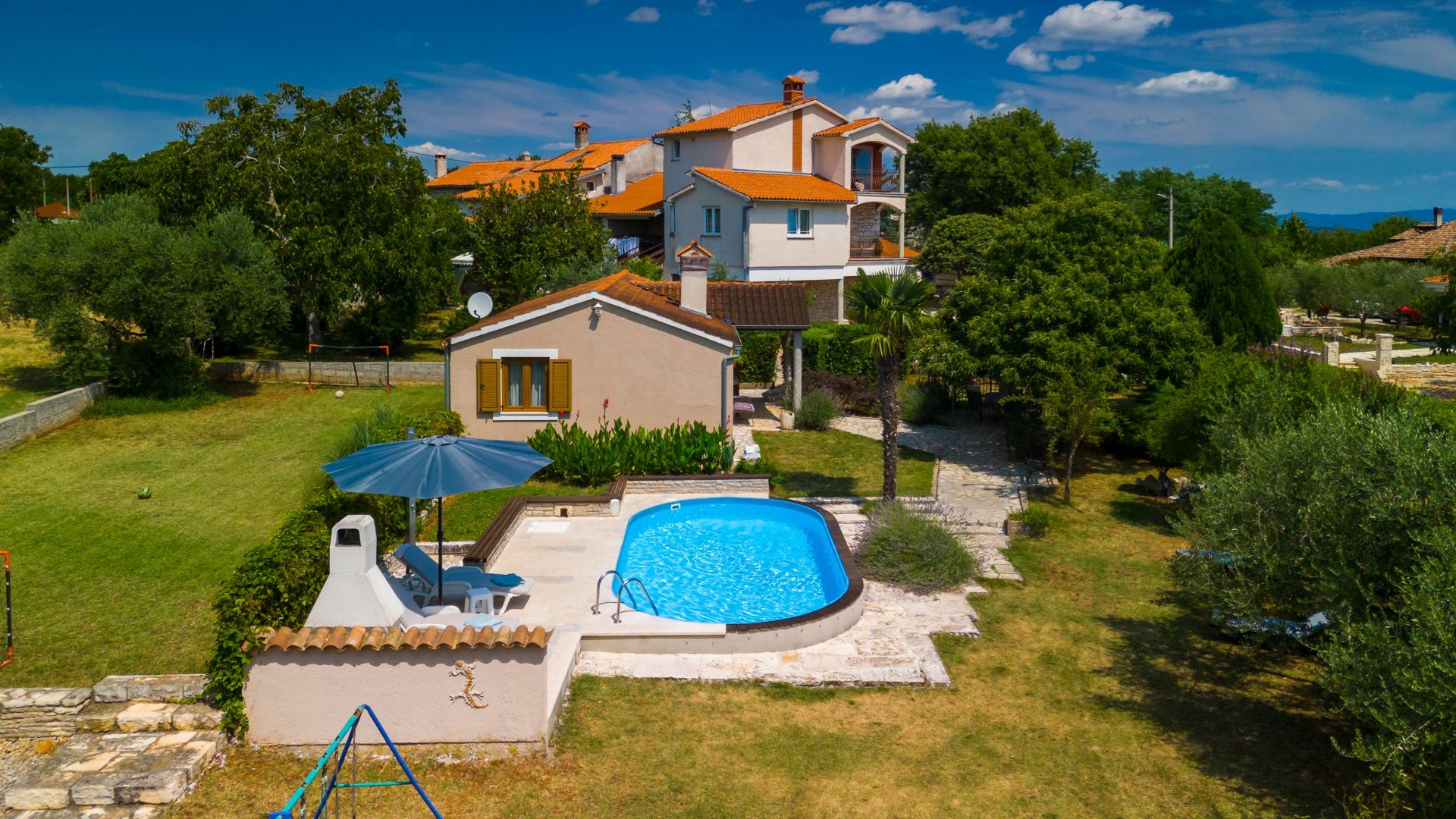 Une propriété résidentielle dotée d’une piscine, d’un patio avec mobilier d’extérieur et d’un jardin bien entretenu.