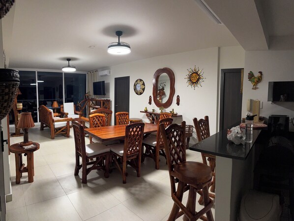 Un comedor con una mesa y sillas de madera, un ventilador de techo y un reloj de pared.
