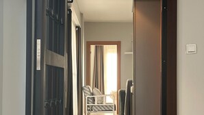 Un couloir menant à une chambre à coucher, où se trouvent un lit, une chaise et un bureau.