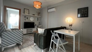 Un salon moderne avec un canapé, un téléviseur et un coin repas.