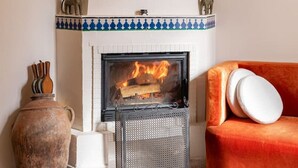Habitació amb una llar de foc, un butac armchair vermell i un vas decoratiu.