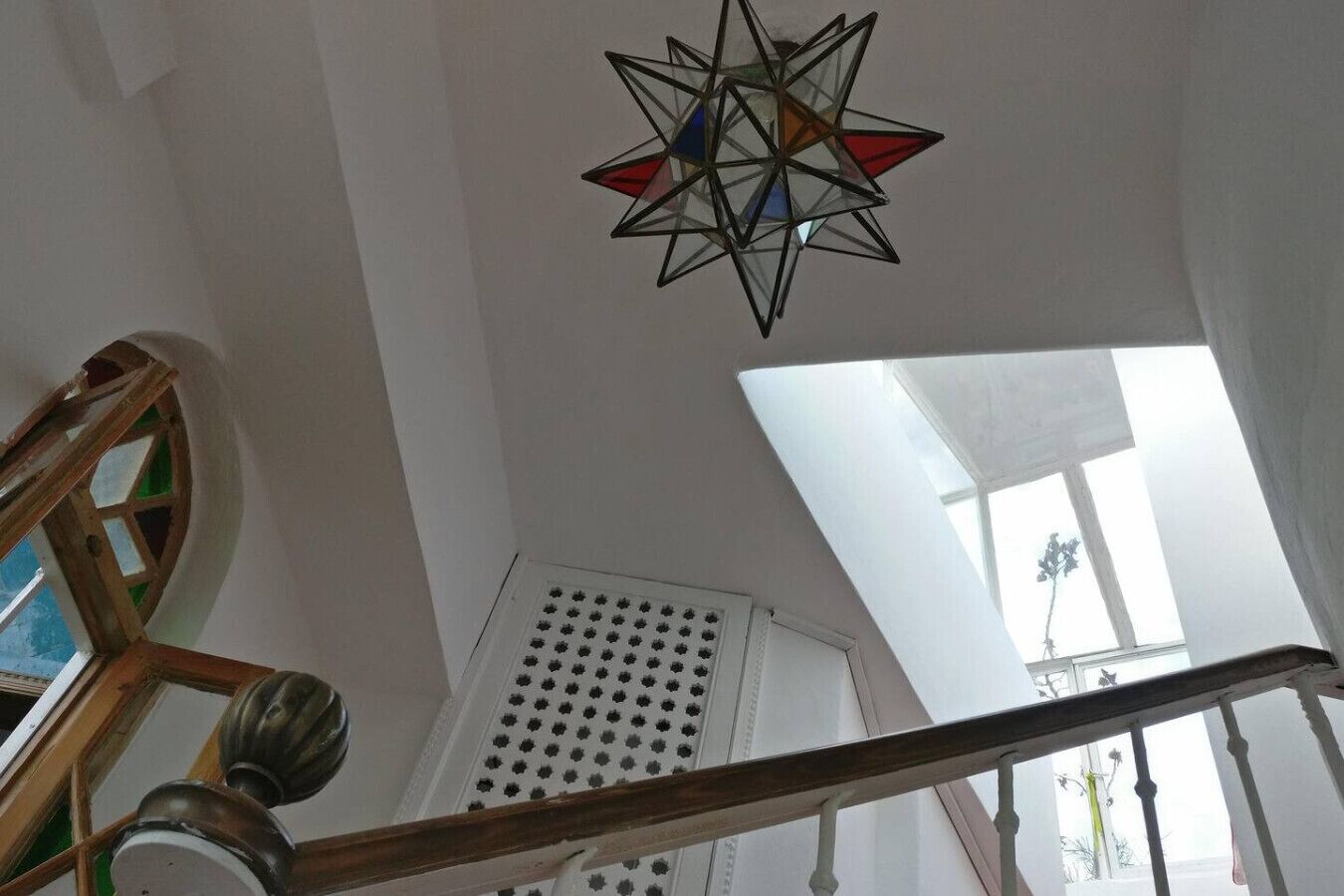 A room with a skylight, a star-shaped stained glass window, and a wooden staircase railing.