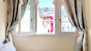 A room with a window featuring a decorative arch and floral curtains. - Absinthe Guesthouse : Charming Suite With Sea View - Battuta Suite (Tangier)