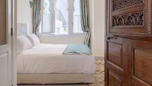 A bedroom with a bed, a window with curtains, and a wooden door with intricate carvings. - Absinthe Guesthouse : Charming Suite With Sea View - Battuta Suite (Tangier)