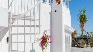 Un edificio blanco con una escalera que lleva a un balcón, rodeado de cielo azul despejado.