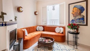 Una sala de estar con sofá, chimenea, ventana con balcón y un cartel en la pared.