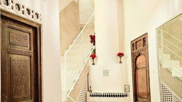 A hallway with a wooden door, a staircase, a fireplace, and a hanging light fixture.