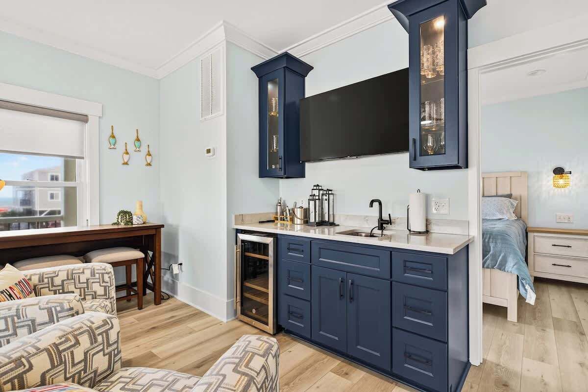Una cocina compacta con horno empotrado, un televisor de pantalla plana grande y una zona de comedor con sillas estampadas.