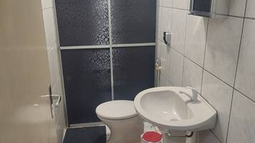 Un baño con inodoro, lavamanos y cabina de ducha.