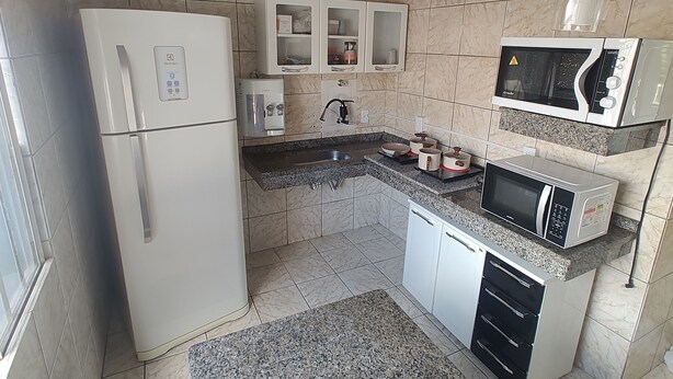 Una cocina equipada con refrigerador, microondas, pileta y alacenas.