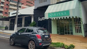 Un edificio con un toldo verde que dice "MI PLACE GELATO" y un coche negro estacionado adelante.