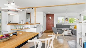 Eine moderne Küche mit weißen Schränken, einem Holzespeisetisch und einem grauen Sofa im Wohnbereich.