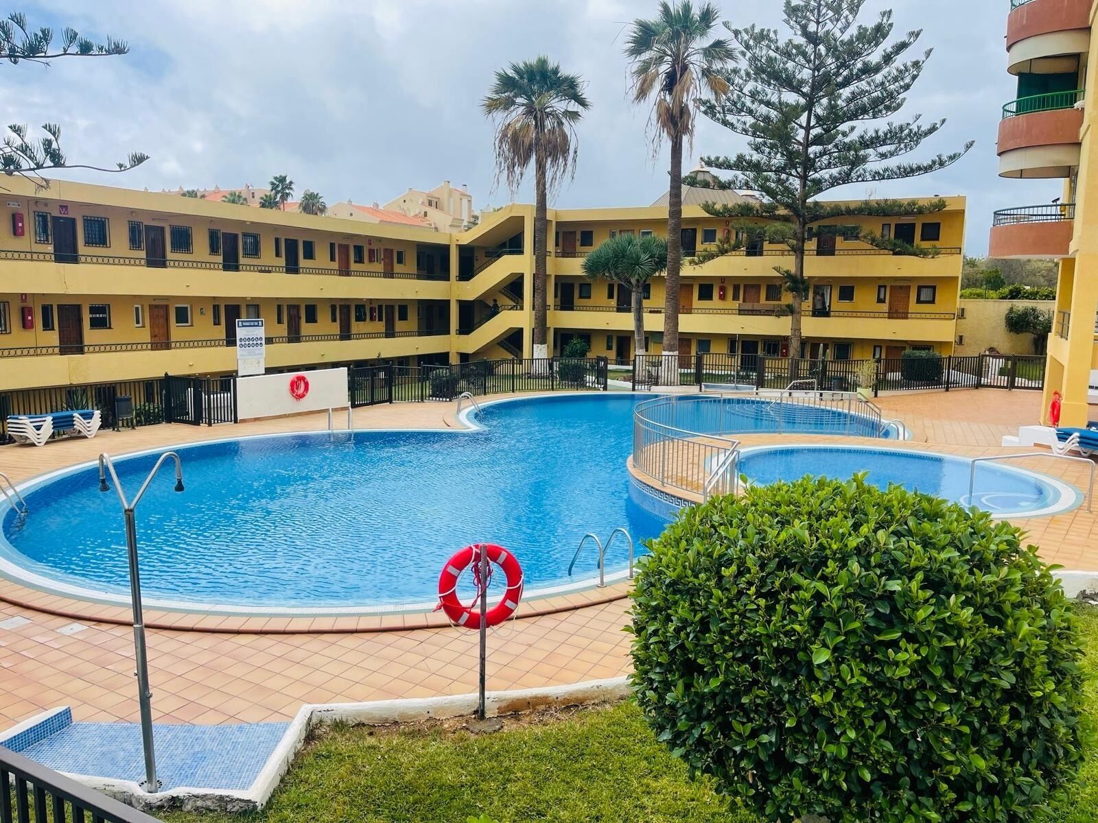 Un hôtel doté d’une grande piscine extérieure, de nombreux balcons et d’une végétation luxuriante.