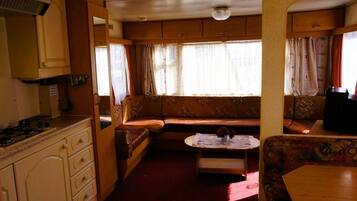 Interior compacto de autocaravana con kitchenette, zona de estar y una mesa.