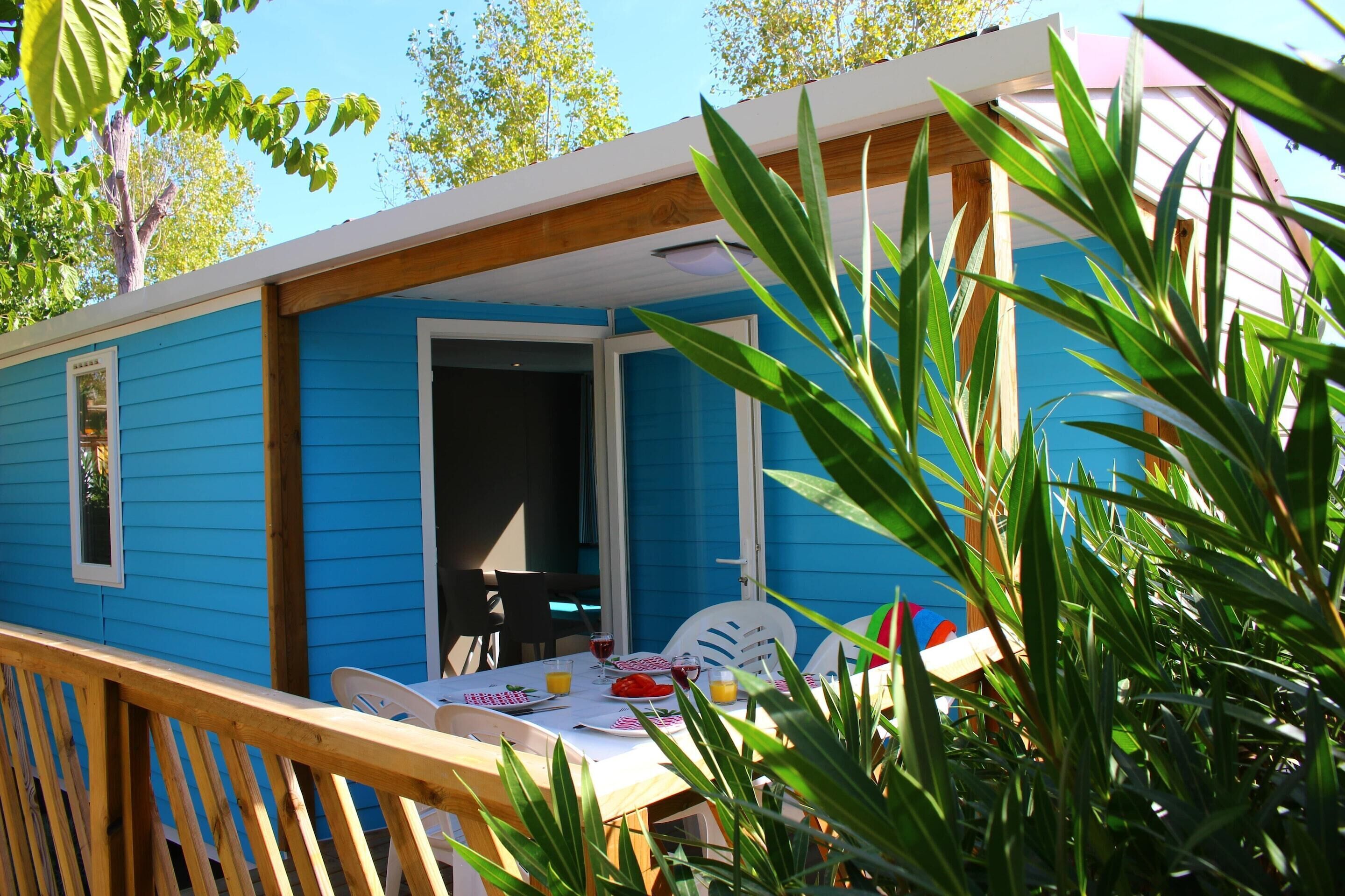 A blue mobile home with a dining area and a table set for two.