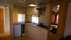 Eine kleine Küche mit Kühlschrank, Spüle, Herd und Schränken.