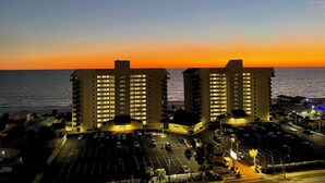 A hotel with a parking lot and a view of the ocean at sunset.