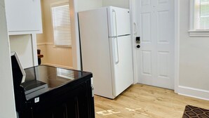 Una cocina compacta con refrigerador, microondas y piso de madera.