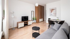 Ett modernt vardagsrum med en grå soffa, ett svart runt bord och en tv som står på ett träskåp.