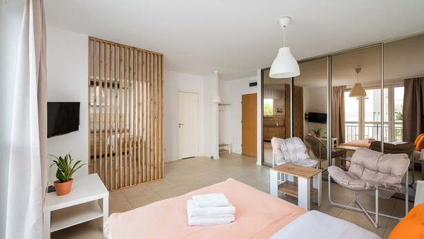 Una habitación de hotel moderna con una cama, un escritorio, una silla, un televisor y un ventanal grande.