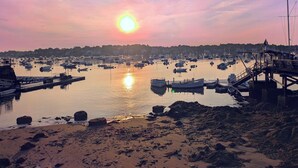 Un port au coucher du soleil, avec des bateaux amarrés et une jetée sur la droite.