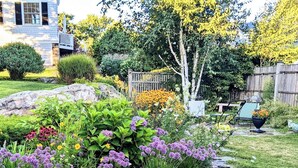 Un jardin bordé de pierres, avec différentes espèces de plantes et une clôture en bois.