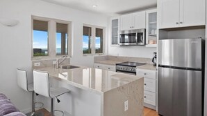 A modern kitchen with white cabinets, stainless steel appliances, and a large island with bar stools.
