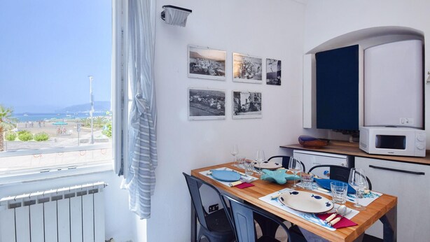A dining area with a view of the sea, a table set with plates and glasses, and a microwave above it. - 1 bedroom awesome apartment in Sestri Levante (Sestri Levante)