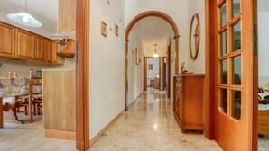 Un pasillo con armarios de madera, piso de mármol y puerta de madera con ventanal.