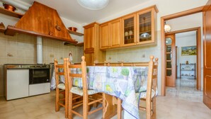 Una cocina con armarios de madera, una mesa de comedor con sillas y un salpicadero de azulejos.