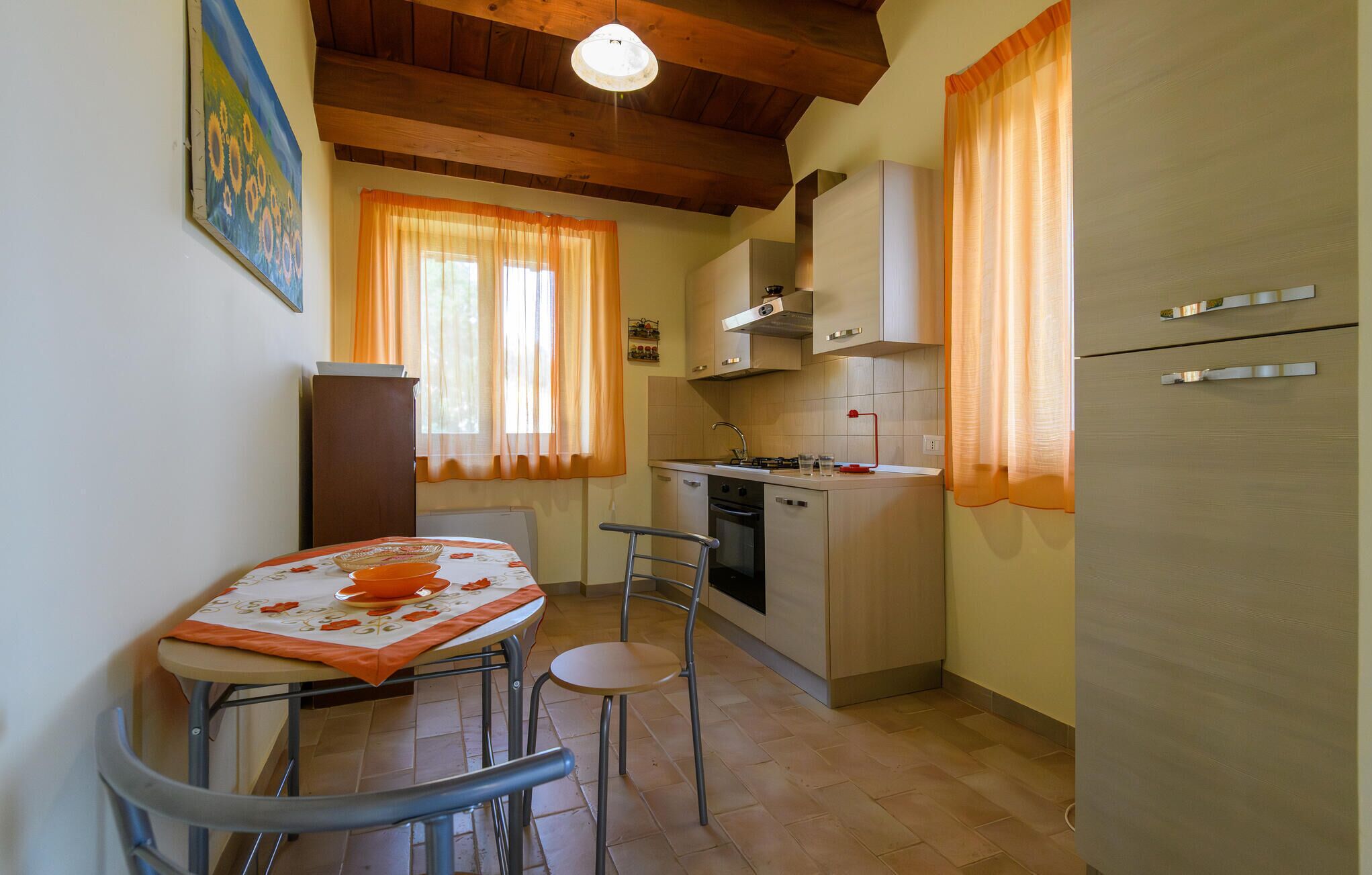 A compact kitchen with a dining table, chairs, a refrigerator, and a stove.