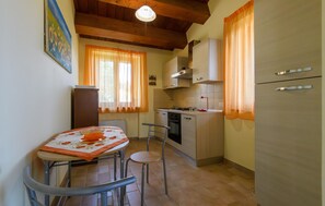 A compact kitchen with a dining table, chairs, a refrigerator, and a stove.