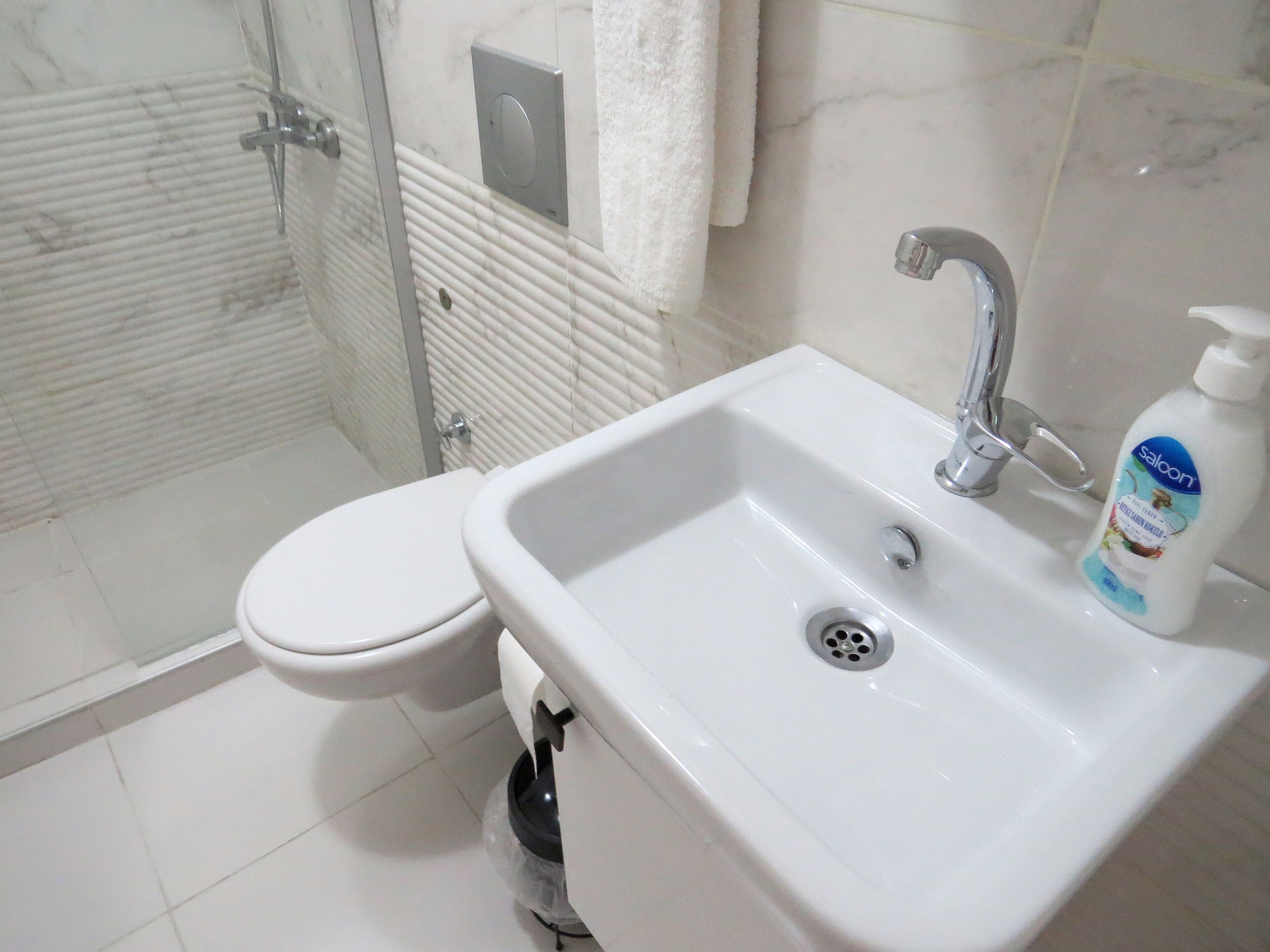 Un baño con un lavamanos blanco, un inodoro y una cabina de ducha de vidrio.
