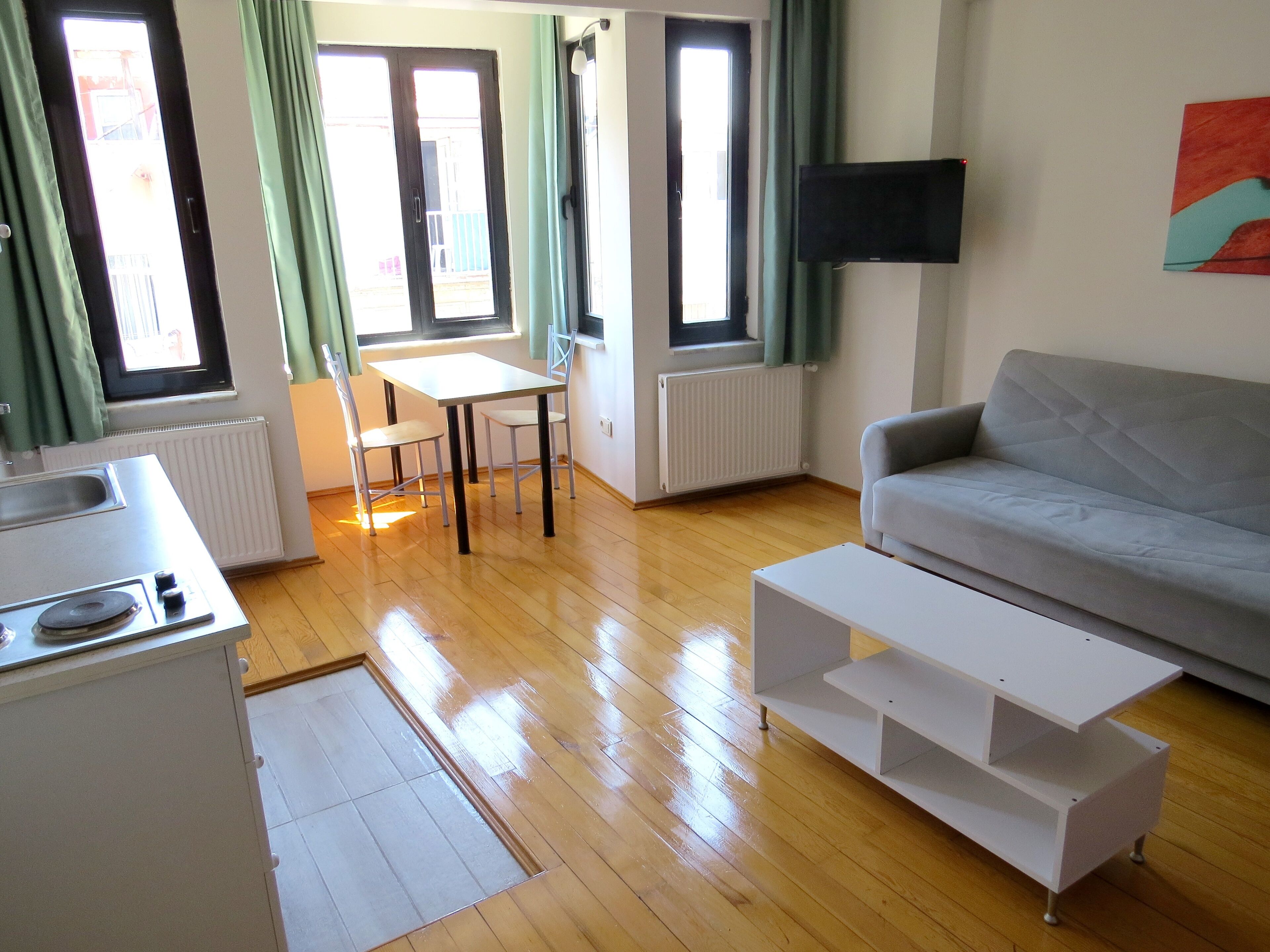 A modern living room with a grey sofa, a white coffee table, and a dining area with a table and chairs.