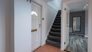 A staircase leading to a second floor with a white door and a decorative metal piece above it. - Spacious 3-bedroom home in central Belfast—walk to Cathedral Quarter (Belfast)