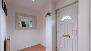 A hallway with a white door, a mirror, and a coat rack. - Spacious 3-bedroom home in central Belfast—walk to Cathedral Quarter (Belfast)