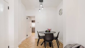 A dining area with a round table, black chairs, and a chandelier. - Modern 2-bed home with free on-street parking, fast Wi-Fi & family amenities. (Belfast)