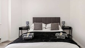 A neatly arranged bedroom with a large bed, two bedside tables, and a black headboard. - Modern 1-bed apartment in Belfast’s Cathedral Quarter. (Belfast)