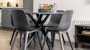 A modern kitchen with grey cabinets, a dining table with four chairs, and a small shelf with snacks. - Modern 1-bed apartment in Belfast’s Cathedral Quarter. (Belfast)