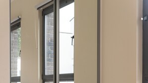 Une pièce dotée d’un grand miroir qui reflète une fenêtre et une porte.