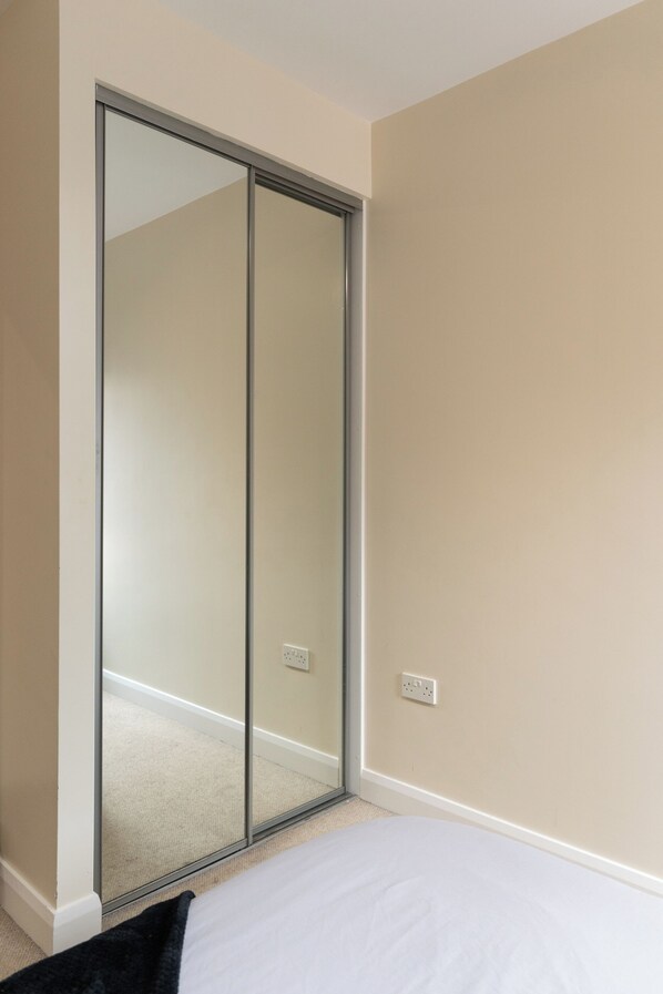 A bedroom with a sliding glass door closet, a bed, and a wall socket.