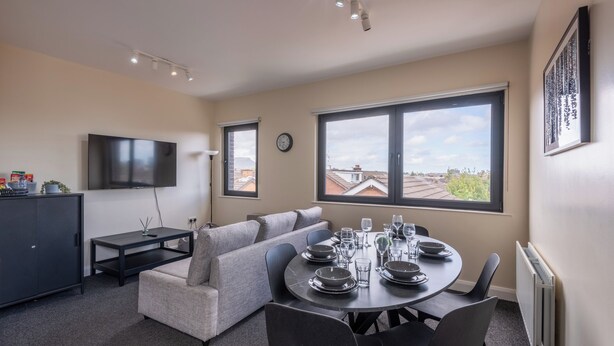 Un salon moderne comprenant un coin repas, un canapé, un téléviseur et une vue sur la ville.