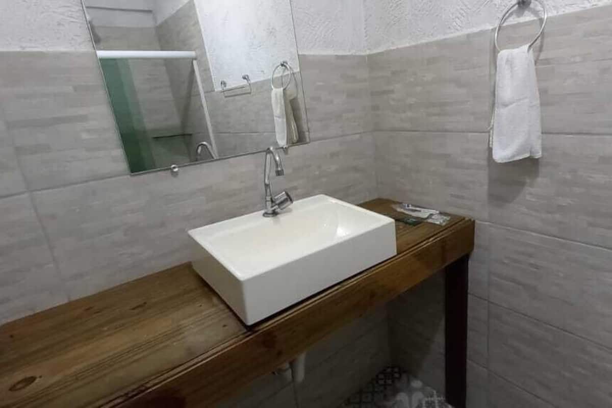 A bathroom with a white sink, wooden vanity, and a mirror.