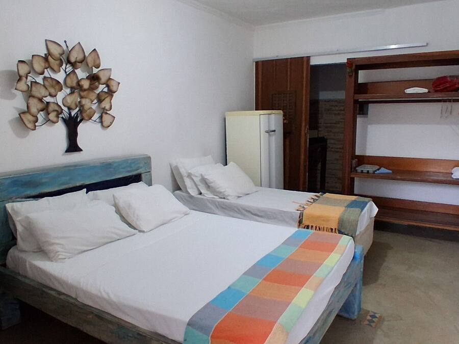 A bedroom with two beds, a wardrobe, a mirror, and a wall decoration.