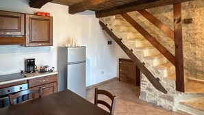 A kitchen with wooden cabinets, a refrigerator, and a dining table.